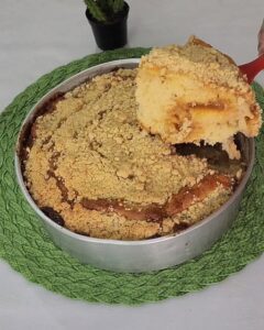 Se existe um doce que representa aconchego, tradição e sabor, é a cuca de banana com farofa. Típica do sul do Brasil, essa delícia une o sabor suave da banana madura com uma farofa crocante e uma massa fofinha, criando um bolo rústico e irresistível. Ideal para servir com um café fresco, ela é perfeita para lanches, cafés da tarde e encontros com amigos ou família. E o melhor: é fácil de preparar e não requer batedeira nem técnicas complicadas. Confira o passo a passo completo e prepare ainda hoje essa maravilha na sua casa! Ingredientes Para a massa: 2 xícaras (chá) de farinha de trigo 1 xícara (chá) de açúcar 1 colher (sopa) de fermento em pó 1/2 xícara (chá) de manteiga (em temperatura ambiente) 2 ovos 1/2 xícara (chá) de leite 4 bananas maduras cortadas em rodelas 1 colher (chá) de essência de baunilha (opcional) Para a farofa: 1/2 xícara (chá) de farinha de trigo 1/2 xícara (chá) de açúcar 1/2 xícara (chá) de manteiga gelada 1 colher (chá) de canela em pó Modo de Preparo 1. Prepare a massa Preaqueça o forno a 180 °C e unte uma forma média (retangular ou redonda) com manteiga e farinha. Em uma tigela, misture a farinha de trigo, o açúcar e o fermento em pó. Adicione os ovos, a manteiga e o leite, mexendo até obter uma massa cremosa e homogênea. Se quiser, acrescente a essência de baunilha para dar um aroma especial. Despeje a massa na forma e alise com uma espátula. Distribua as rodelas de banana por cima, cobrindo toda a superfície da massa. 2. Prepare a farofa crocante Em uma tigela, adicione a farinha de trigo, o açúcar, a canela e a manteiga gelada em cubos. Com as pontas dos dedos, misture até formar uma farofa grossa, úmida e granulada. Espalhe a farofa uniformemente por cima das bananas. 3. Asse a cuca Leve ao forno preaquecido por 40 a 45 minutos, ou até a massa estar assada e a farofa dourada. Faça o teste do palito: espete no centro e, se sair limpo, a cuca está pronta. Retire do forno e deixe esfriar levemente antes de cortar. Dicas para uma cuca perfeita Use bananas bem maduras: Elas ficam mais doces e intensificam o sabor da receita. Farinha de trigo peneirada: Deixa a massa mais leve. Não misture demais a massa: Apenas o suficiente para incorporar os ingredientes. Mais crocância: Acrescente aveia ou castanhas picadas na farofa. Para servir quente: Aqueça ligeiramente no forno e sirva com uma bola de sorvete de creme. Variações da receita Cuca de maçã com farofa: Substitua a banana por fatias finas de maçã e adicione gotas de limão. Cuca recheada: Acrescente doce de leite ou geleia no meio da massa antes de colocar as bananas. Versão integral: Use farinha integral e açúcar mascavo para uma opção mais saudável. Com chocolate: Polvilhe gotas de chocolate junto da farofa para um toque especial. Quando servir? Essa receita é perfeita para: Café da manhã reforçado Lanche da tarde com café coado Aniversários, reuniões e encontros familiares Servir como sobremesa após refeições Vendas de bolos caseiros ou festas juninas Como armazenar Temperatura ambiente: até 3 dias em local seco e coberto Geladeira: até 5 dias em pote fechado Freezer: pode congelar em pedaços por até 30 dias (sem a banana escurecer) Conclusão A cuca de banana com farofa é uma receita clássica, com sabor de afeto e simplicidade. Perfeita para todos os momentos, ela une o doce da banana, a cremosidade da massa e a crocância da farofa em uma combinação que conquista desde o primeiro pedaço. Agora que você tem o passo a passo completo, que tal preparar ainda hoje? Sirva com café fresco e aproveite cada fatia dessa delícia tradicional!